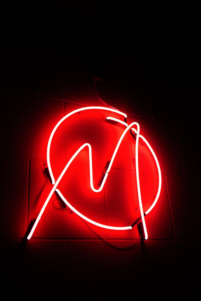 Bright red neon sign in artistic design on a dark background, creating a striking visual contrast.